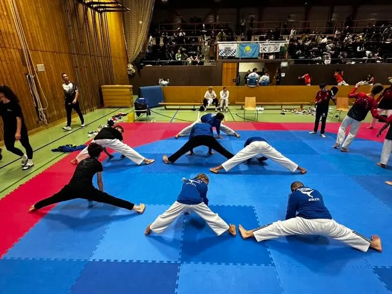 Sportler unseres Teams dehnen sich vor den Kämpfen im Spagat auf der Wettkampffläche