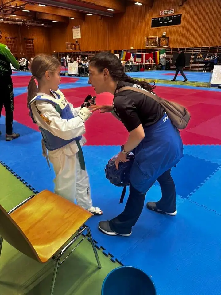 Unsere Trainerin spricht am Mattenrand mit einer jungen Sportlerin in Schutzausrüstung