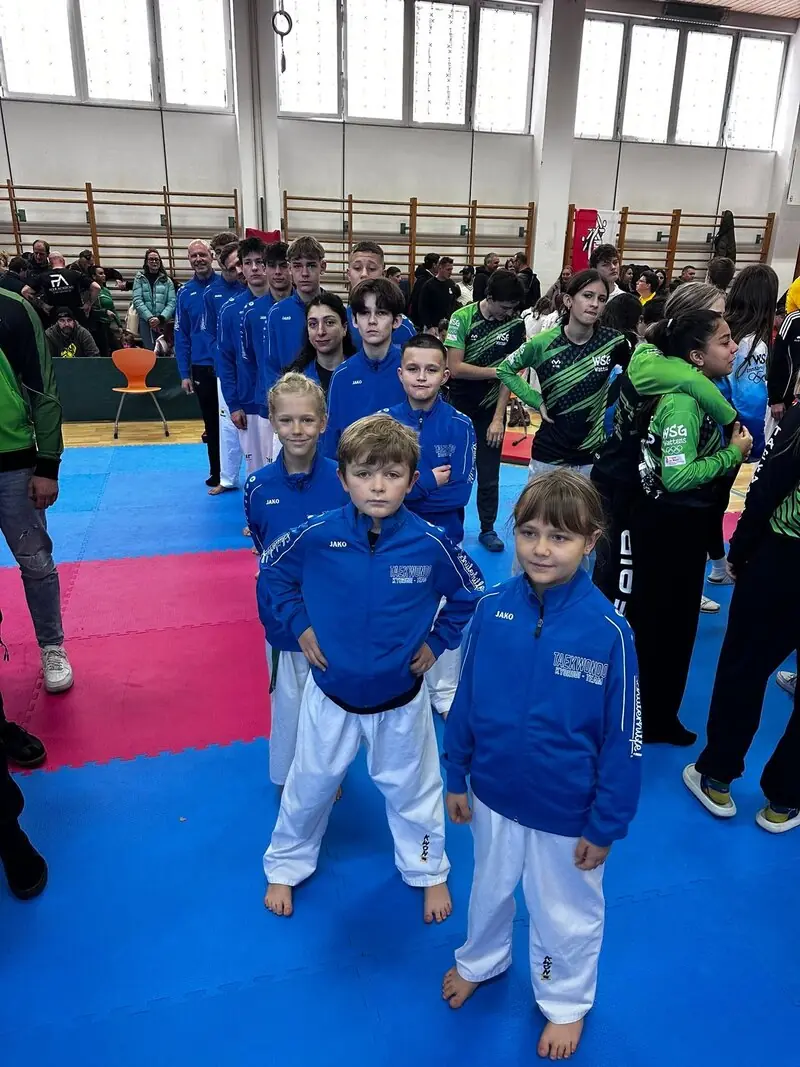 Unsere jüngeren Sportlerinnen und Sportler in blauen Vereinsjacken aufgereiht auf der Wettkampffläche
