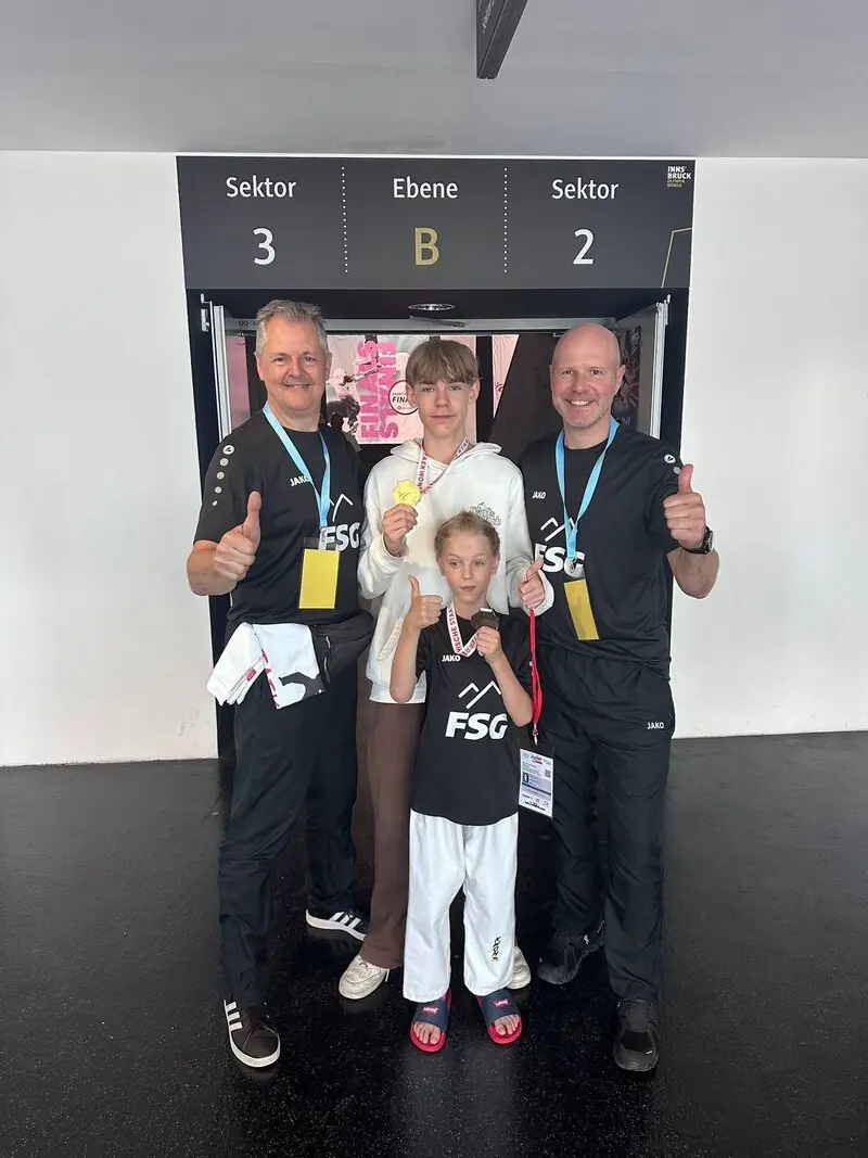 Zwei Trainer mit zwei jungen Medaillengewinnern am Eingang zu den Tribünen der Olympiahalle Innsbruck